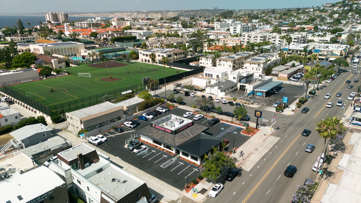 Wide aerial view of La Jolla Village near El Pueblo, with the ocean and bluffs in the distance